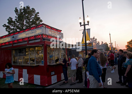 A dusk image of a concession stand on the midway of the Utah State Fair. A little girl appears to have gotten her meal already. Stock Photo