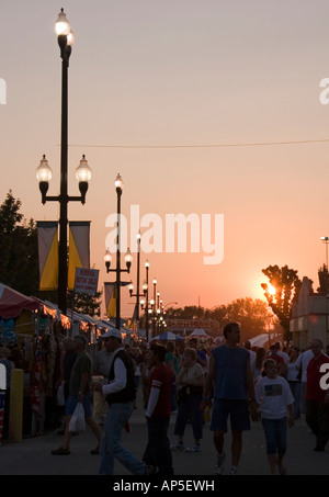 Patrons & visitors of the Utah State Fair walking the midway as nightfall approaches. The sun is almost set & all is in shadow. Stock Photo