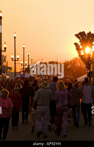 Patrons & visitors of the Utah State Fair walking the midway as nightfall approaches. The sun is almost set & all is in shadow. Stock Photo