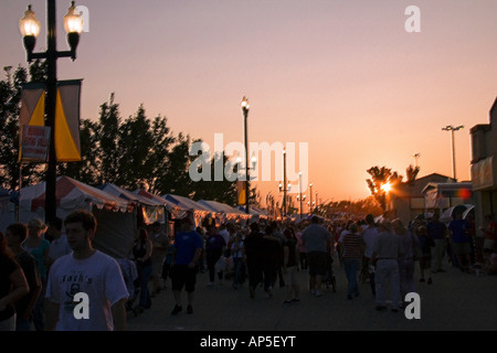 Patrons & visitors of the Utah State Fair walking the midway as nightfall approaches. The sun is almost set & all is in shadow. Stock Photo