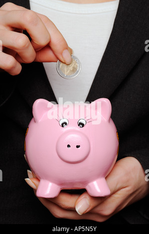 Savings Image of a Business Woman Putting a Euro Coin Into a Piggy Bank Stock Photo