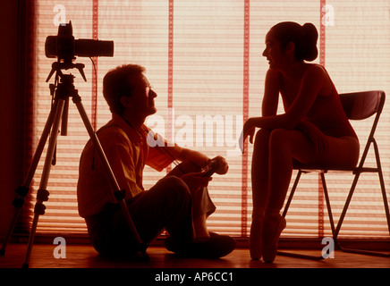 Photographer and model in silhouette working in photo studio relaxed talking Stock Photo