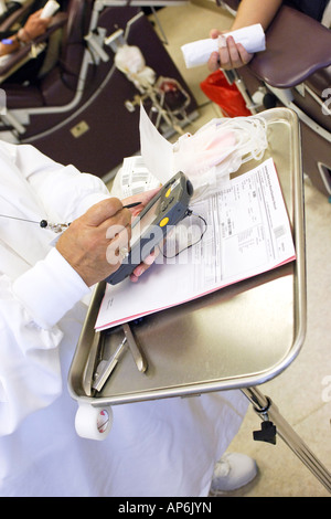 Close up of a Nurse checking a patients data into a PDA machine prior to taking blood Stock Photo