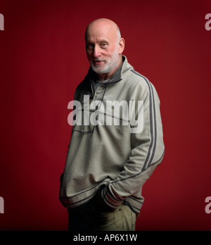 Middle aged man with hand in pocket standing in front of red background Stock Photo