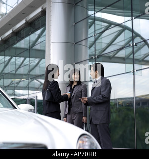 Two businesswomen and man exchanging business cards Stock Photo