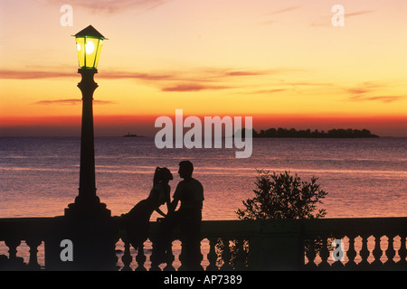 Couple on wall at sunset under lamp in Colonia del Sacramento in Uruguay Stock Photo