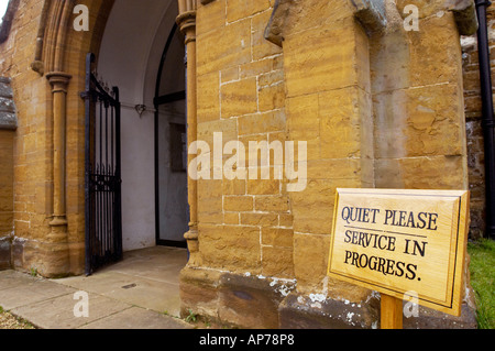 Wooden sign with the wording Quiet Please Service in Progress, placed outside a church entrance Stock Photo