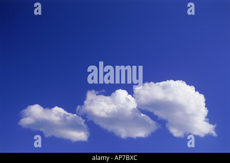 Family of three clouds passing through clear blue skies Stock Photo
