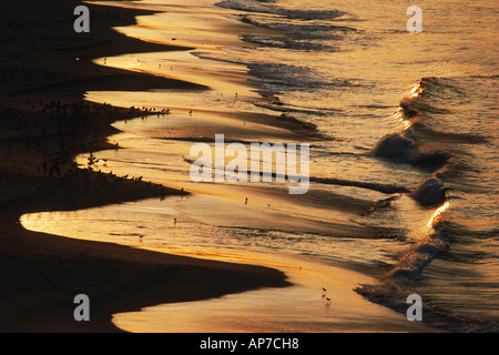 Wave patterns reflecting sunrise light across sandy shore in Laguna Beach, California Stock Photo