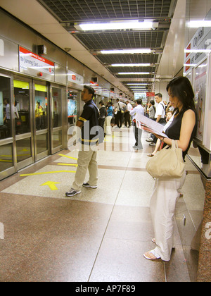 Passengers waiting for train to arrive at City Hall MRT Station Singapore Stock Photo