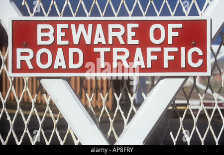 Bold metal sign painted white on scarlet red and fixed on white timber and mesh gate stating Beware of Road traffic Stock Photo