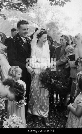 OLD BLACK AND WHITE FAMILY PHOTOGRAPH SNAP SHOT PORTRAIT OF YOUNG COUPLE AND GUESTS ON THEIR WEDDING DAY CIRCA 1950 Stock Photo