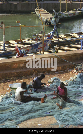 Three men mending fishing nets on the beach Cape Coast Central Ashanti region of Ghana West Africa Stock Photo