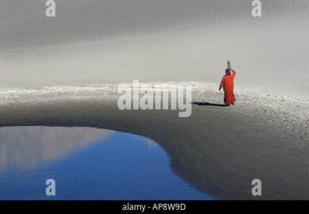 Buddhist monk in desert with motorbike wheel Stock Photo