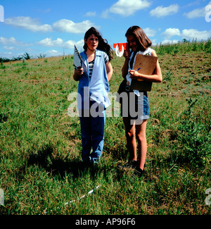 Two students Geography fieldwork studying land use using a clinometer to measure a slope gradient Stock Photo