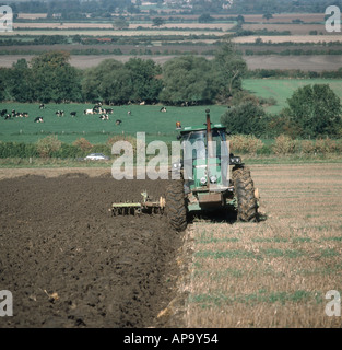 John Deere tractor ploughing stubble field on an organic farm Stock Photo