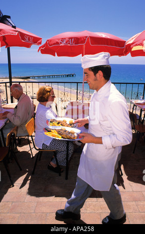 Portugal, Algarve: Waiter serving grilled fish in restaurant Ruinas in Albufeira Stock Photo