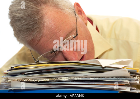 An exhausted senior businessman has fallen asleep on his work Stock Photo