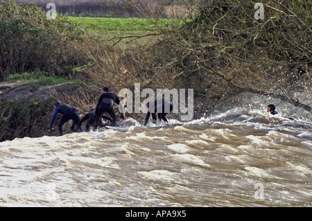 Surfers riding the Severn Bore at Minsterworth in Gloucestershire England Stock Photo