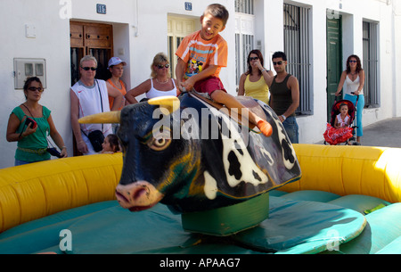 Young boy riding bucking mechanical bull Stock Photo