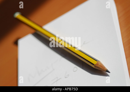 Sharp pencil lying on top of white paper notepad on an office desktop Stock Photo