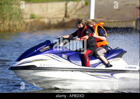 young woman in wetsuit driving a yamaha 4 stroke AF1030 waverider with young boy passenger at speed Stock Photo