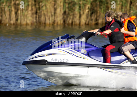 young woman in wetsuit driving a yamaha 4 stroke AF1030 waverider with young boy passenger at speed on the river bann Stock Photo