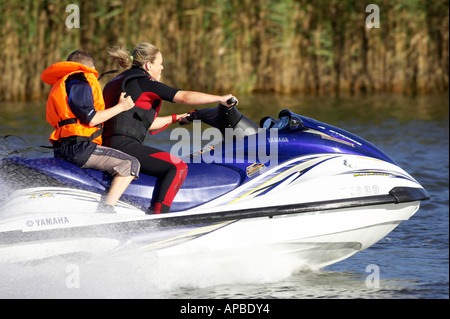 young woman in wetsuit driving a yamaha 4 stroke AF1030 waverider with young boy Stock Photo