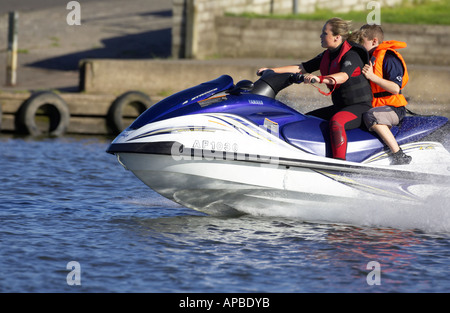 young woman in wetsuit driving a yamaha 4 stroke AF1030 waverider with young boy passenger at speed on the river bann Stock Photo