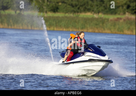 young woman in wetsuit driving a yamaha 4 stroke AF1030 waverider with young boy passenger at speed Stock Photo