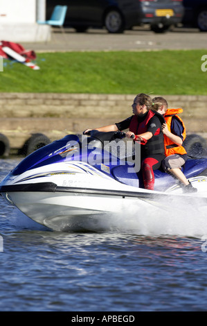 young woman in wetsuit driving a yamaha 4 stroke AF1030 waverider with young boy passenger at speed on the river Stock Photo