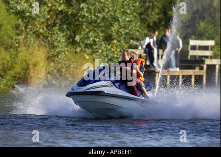 young woman in wetsuit driving a yamaha 4 stroke AF1030 waverider with young boy passenger at speed Stock Photo