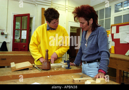 Tutor assist adult in woodwork adult education class Southwark London UK Stock Photo