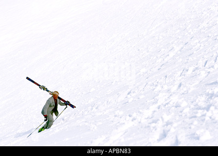 Man walking up steep skislope in business suit Stock Photo