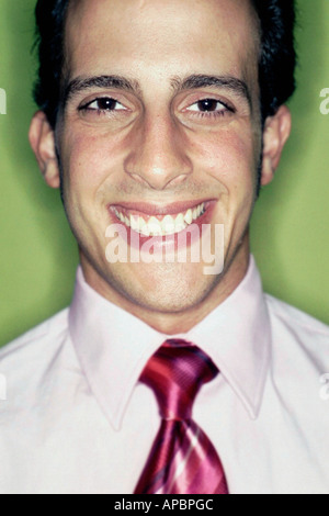Tightly Cropped Head and Shoulders Portrait of Young Businessman Looking into Lens He is Smiling and is Wearing a Shirt and Tie Stock Photo