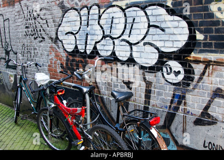 Bicycles lined up next to graffiti art on wall in Amsterdam Holland Stock Photo