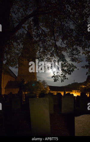 Full moon shining through leaves of trees above graveyard stones in St Brannock’s Parish Church Braunton Devon England Stock Photo