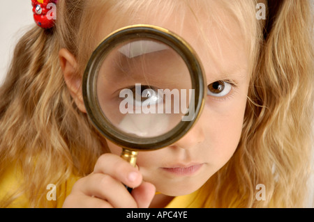 Girl looking through magnifying glass Stock Photo