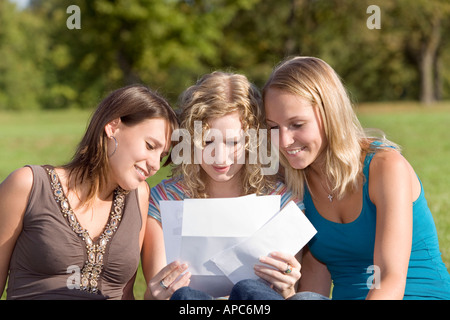 Three young women reading a letter together Stock Photo