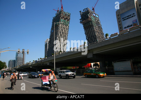 China CCTV Tower building under construction, and pedal-taxi in local traffic, central Beijing. Stock Photo