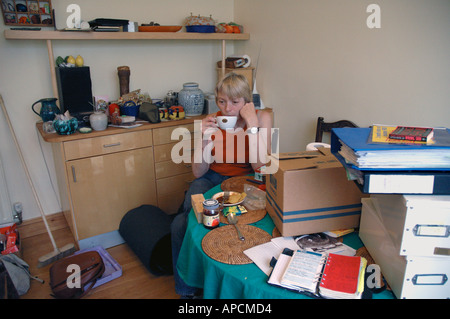 Woman having cup of tea fed up and depressed by housework general domestic cleaning. Stock Photo