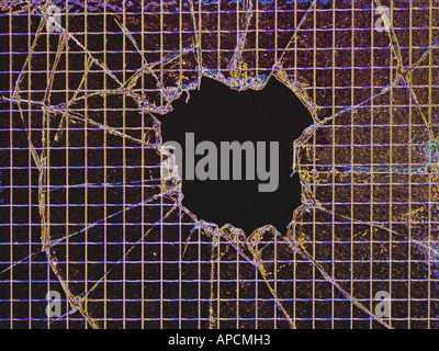 Broken pane of glass with central hole looking into darkness. Stock Photo