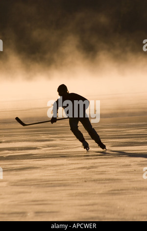 A skater and mist on frozen Donner Lake California at sunrise Stock Photo