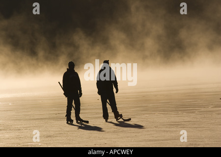 Two skaters and mist on frozen Donner Lake California at sunrise Stock Photo