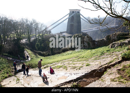 Children playing on rock slide overlooking Isambard Kingdom Brunel's Clifton Suspension Bridge spanning the Avon Gorge, Clifton. Stock Photo