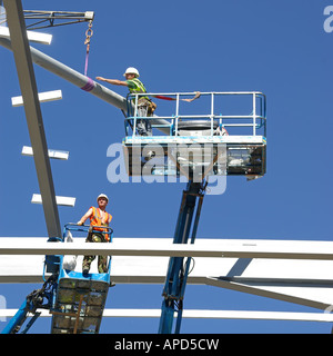 Steel erectors on two cherry pickers access platform during installation of steel framed building Stock Photo