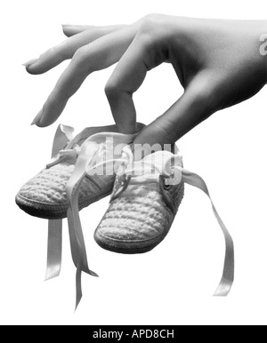 Mothers hand holding a pair of baby shoes Stock Photo