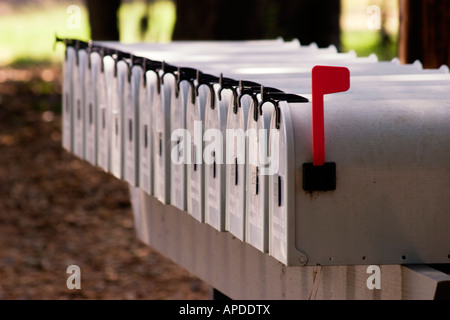 Long row of metal mailboxes with one red flag raised Stock Photo
