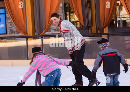 Two children chasing their father while skating at Northstar ski resort near Truckee, California Stock Photo