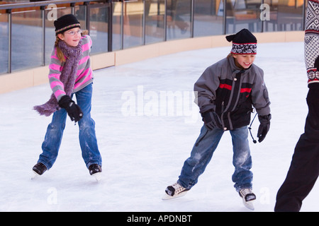 Two children chasing their father while skating at Northstar ski resort near Truckee, California Stock Photo